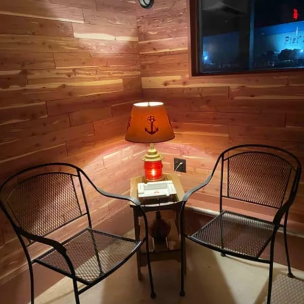 Cozy corner with two black metal chairs, a wooden side table, and a nautical-themed lamp.