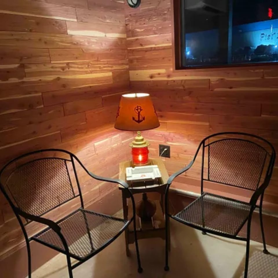 Cozy corner with two black metal chairs, a wooden side table, and a nautical-themed lamp.