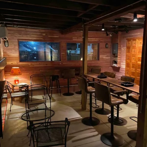 Interior of On the River Tavern & Mo’s Cigar Bar with wooden walls, tables, and chairs.